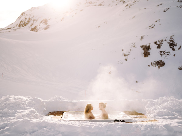 Paar geniesst ein Bad im Aussenwhirlpool vom Iglu-Dorf Davos Klosters